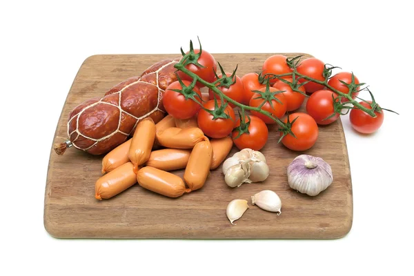 Salchichas y verduras en una tabla de cortar —  Fotos de Stock