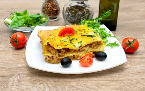 Appetizing lasagna with tomato and olives on a plate. — Stock Photo, Image