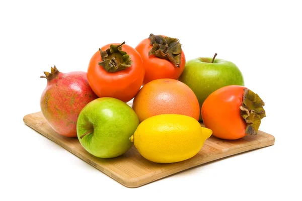 Ripe fruit on a wooden cutting board closeup on white background — Stock Photo, Image