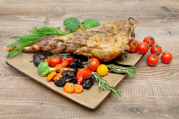 Roasted leg of lamb with vegetables, greens and prunes on a plat — Stock Photo, Image