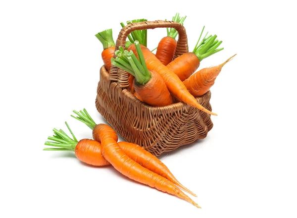 Zanahorias maduras en una canasta de mimbre sobre un fondo blanco de cerca —  Fotos de Stock