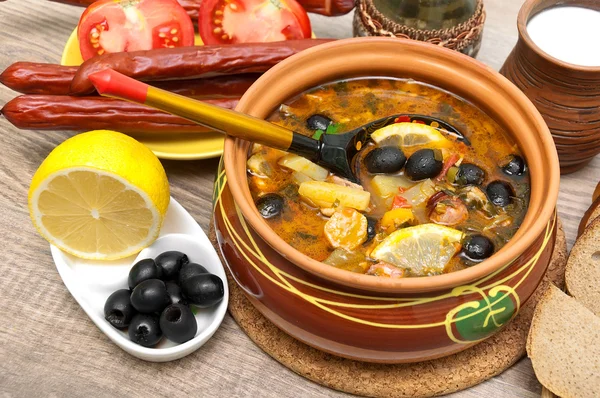 Dish of russian hodgepodge soup and other food on a wooden table — Stock Photo, Image
