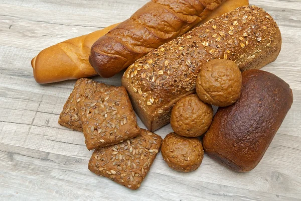 Fresh bread of different varieties on wooden background — Stock Photo, Image