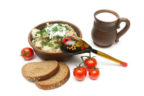 Russian dumplings in a clay bowl, bread, milk and tomatoes on a — Stock Photo, Image