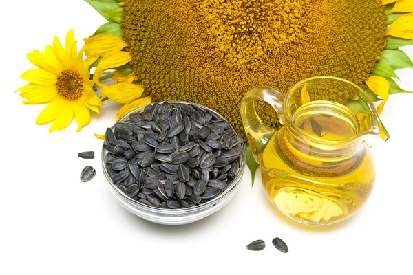 Sunflower oil, sunflower seeds, and flowers on a white backgroun — Stock Photo, Image