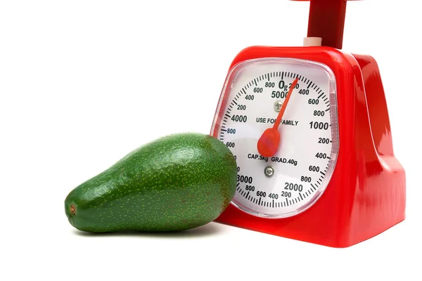 Ripe avocado and kitchen scales on a white background — Stock Photo, Image