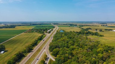 Drone shot of an interstate highway in the Midwest showing farms and open fields in mid September