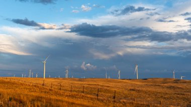 Rüzgar türbinleri sabahın erken saatlerinde arka planda bulutlarla birlikte altın ışıkta