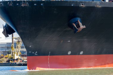 Güneşli bir günde dar bir kanalda giden büyük bir konteynır gemisinin pruvası.