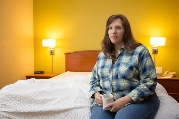 Vrouw alleen in een hotelkamer op zoek triest houden een koffiemok — Stockfoto
