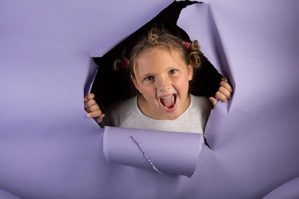 Menina tola com cabelo louco rasgando através de um pano de fundo roxo — Fotografia de Stock