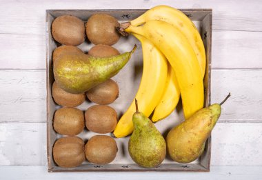 Muzlar, konferans armutları ve kiviler eski ahşap zemin üzerinde eski bir ahşap tepsiye yerleştirilmiş..