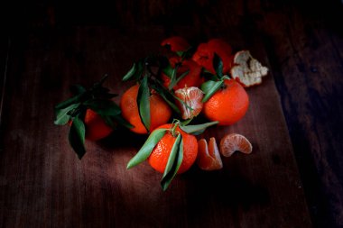 Eski ahşap bir masanın üzerinde yaprakları olan Clementines.