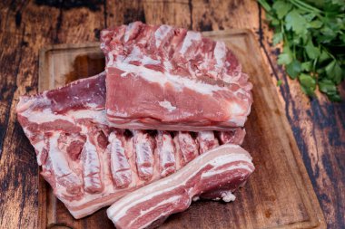 Eski ahşap bir masada duran kullanılmış bir kesme tahtasının üzerinde taze domuz göbeği.