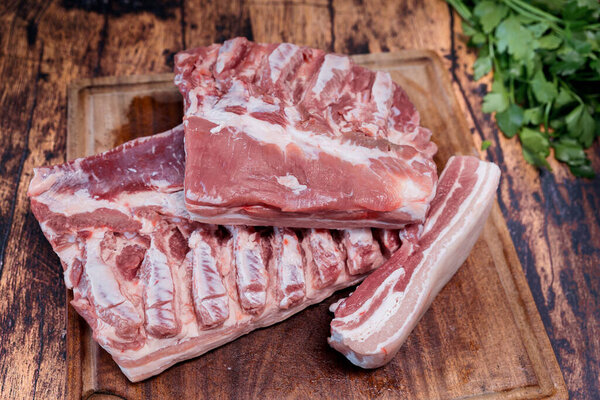 fresh pork belly on a used cutting board resting on an old wooden table