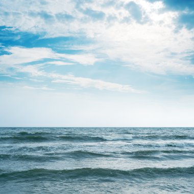 Deniz ve güneş ile bulutlu gökyüzü üzerinde sallayarak