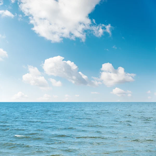 Waving sea and cloudy sky with sun over it Stock Photo