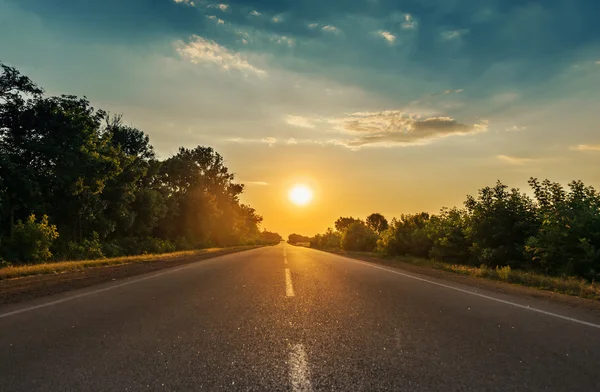 Słońce w horyzont nad droga asfaltowa — Zdjęcie stockowe