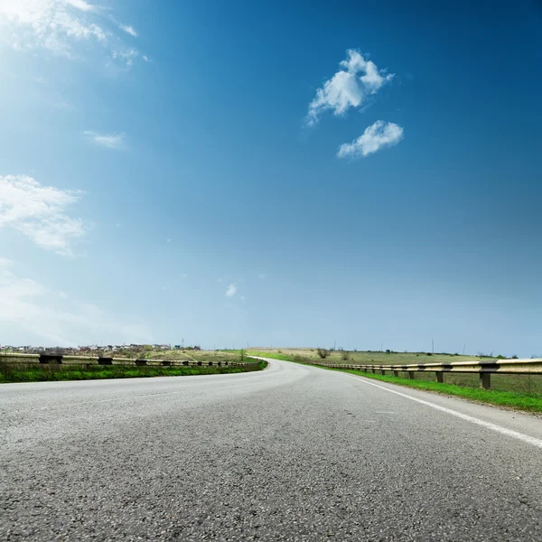 Асфальтовая дорога до горизонта крупным планом и голубое небо с облаками — стоковое фото