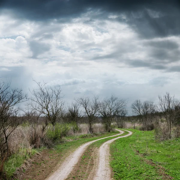 Estrada suja sob céu dramático na primavera — Fotografia de Stock