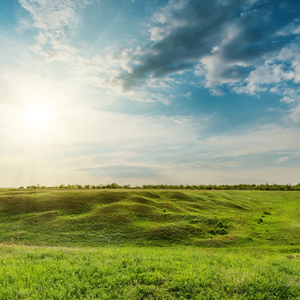 Sunset in dramatic clouds over green meadow — Stock Photo, Image