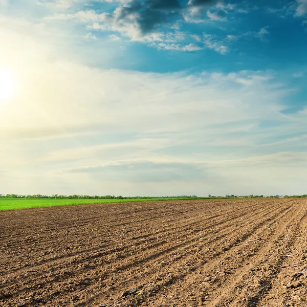 Black agriculture field in spring and sunset in clouds — Stock Photo, Image