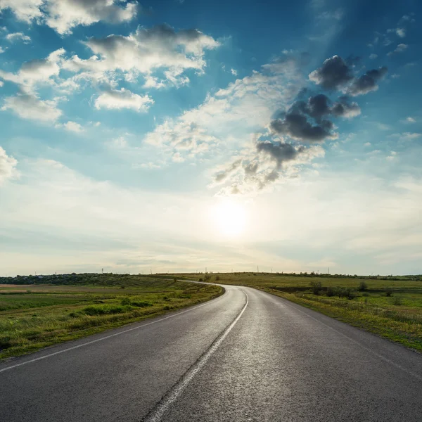 Sunset in clouds over asphalt road — Stock Photo, Image