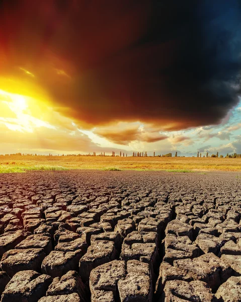 Low dark clouds in sunset and drought earth closeup — Stock Photo, Image