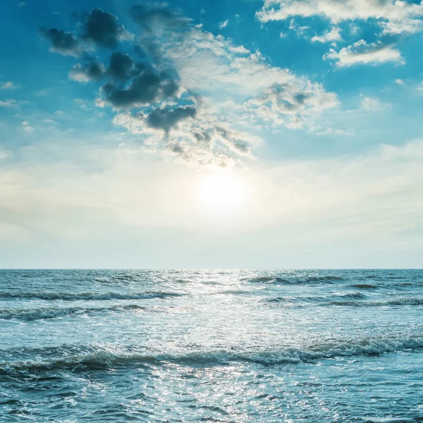 Låga solen i blå himmel över havet med våg — Stockfoto