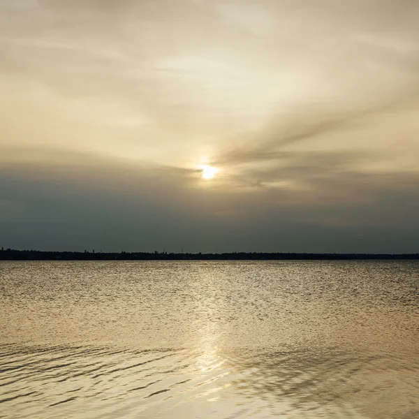 Nízké slunce v mracích nad řekou — Stock fotografie