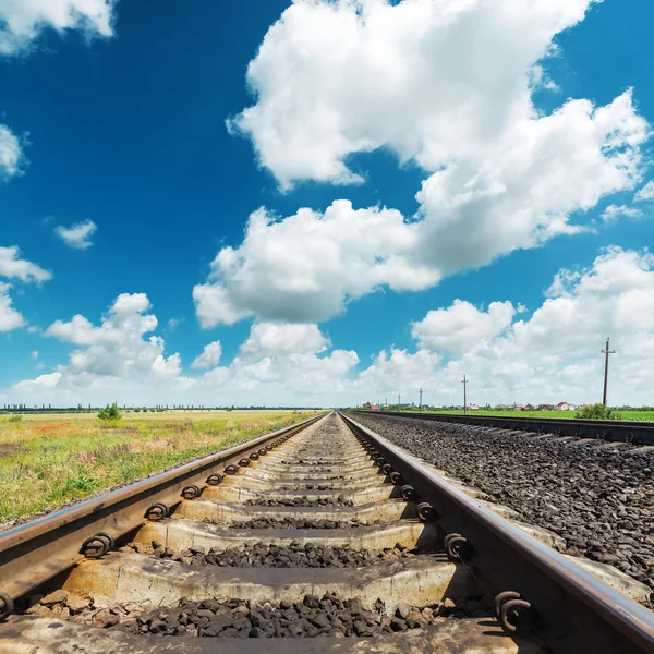 Spoorweg naar horizon close-up onder wolken in diepblauwe lucht — Stockfoto