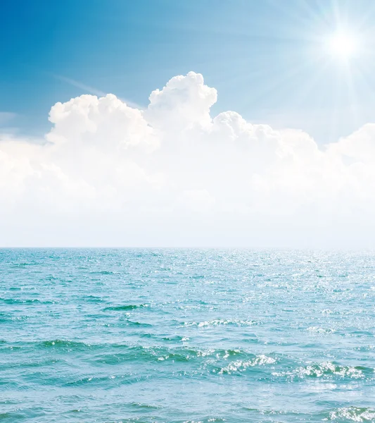 Белые облака в синем небе с солнцем и морем — стоковое фото