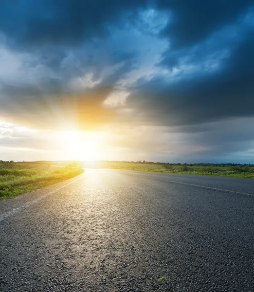 Coucher de soleil dans les sombres nuages bas sur route asphaltée — Photo