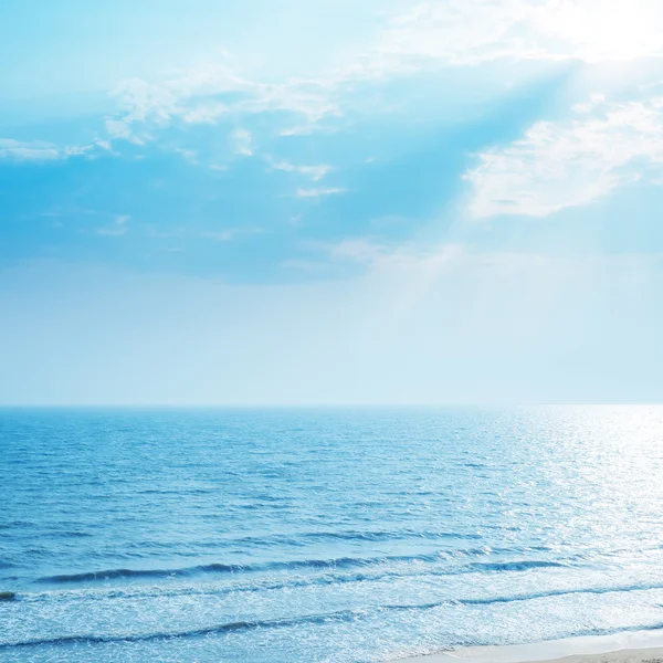 Blick auf das Meer mit Reflexionen und Sonnenstrahlen in den blauen Himmel — Stockfoto