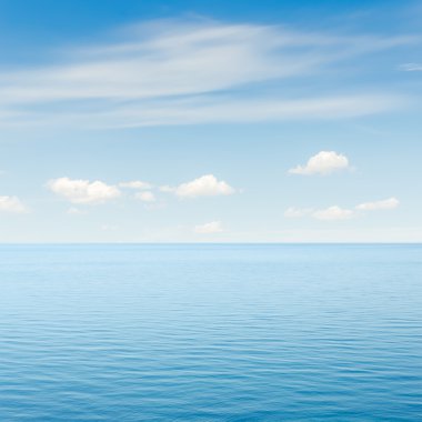 Mavi deniz ve gökyüzü bulutlarla kaplı.