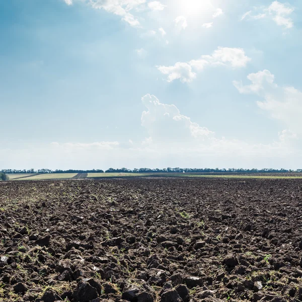 Sol en las nubes sobre el campo negro después de la cosecha — Foto de Stock