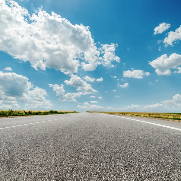 Carretera asfaltada al horizonte y las nubes sobre él — Foto de Stock