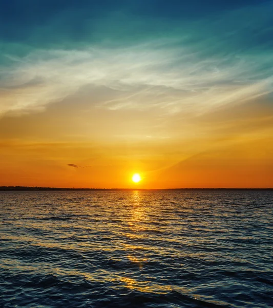 Oranje zonsondergang over het donkere water — Stockfoto