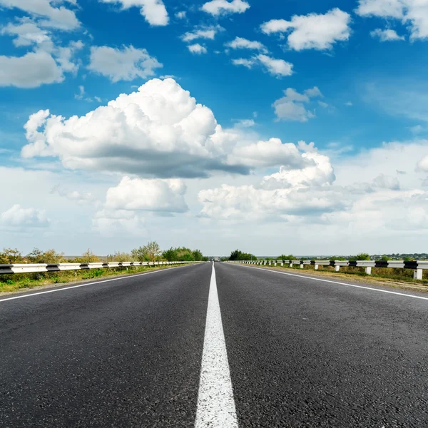 Estrada de asfalto com linha branca e céu azul com nuvens por cima — Fotografia de Stock