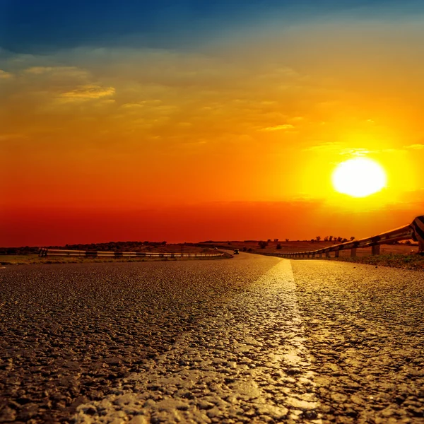 Pôr-do-sol vermelho sobre estrada de asfalto — Fotografia de Stock