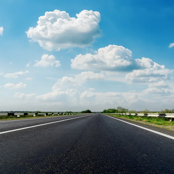 Gros plan route d'asphalte et des nuages bas dans le ciel bleu — Photo