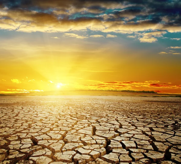 Calentamiento global. dramático atardecer sobre tierra agrietada — Foto de Stock