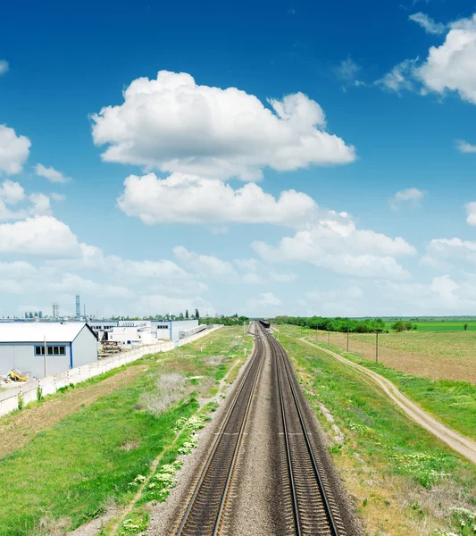 Två järnvägen till horisonten i grönt landskap under blå himmel med cl — Stockfoto