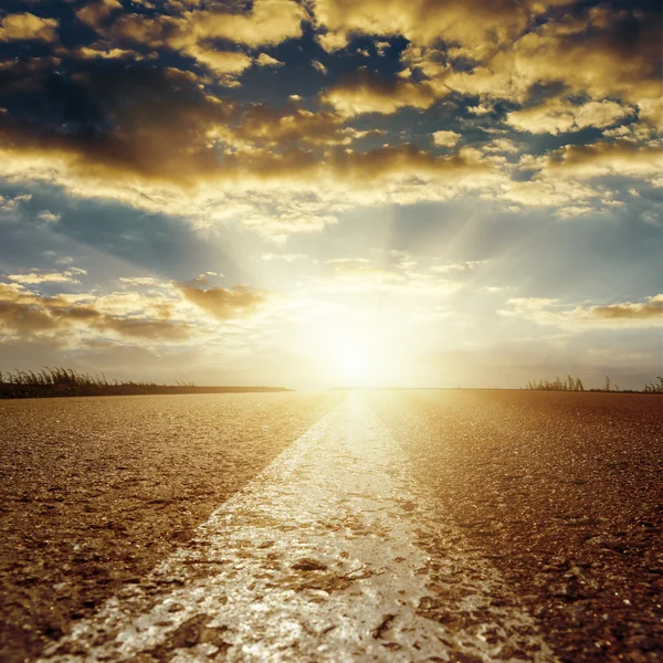 Puesta de sol en las nubes bajas sobre camino de asfalto con línea blanca central — Foto de Stock