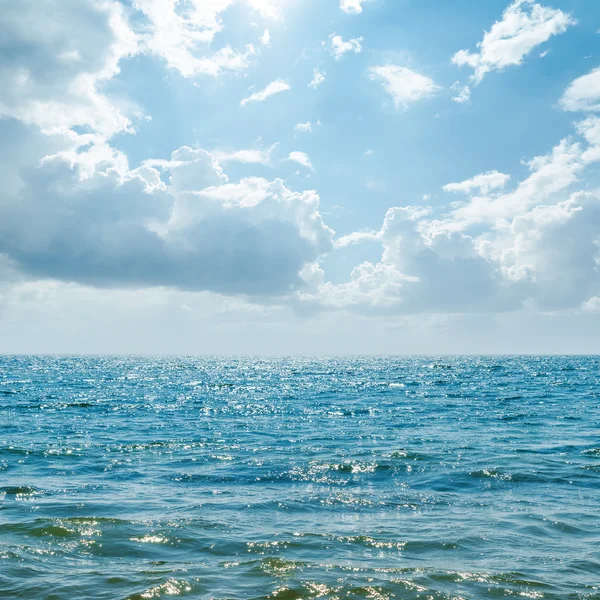 Blauwe zee met zon in de wolken — Stockfoto