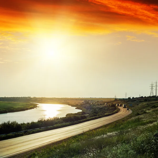 Roten Sonnenuntergang über Asphaltstraße nahe Fluss — Stockfoto