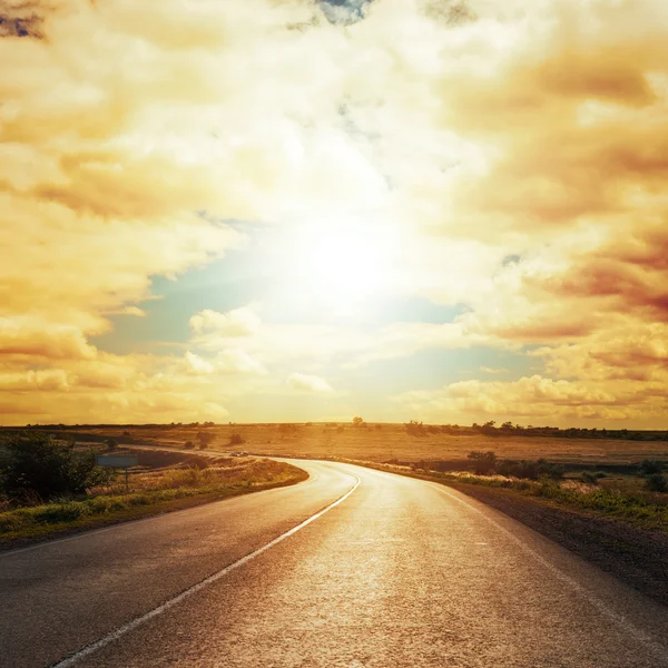 Dramatic sunset in clouds over asphalt road — Stock Photo, Image