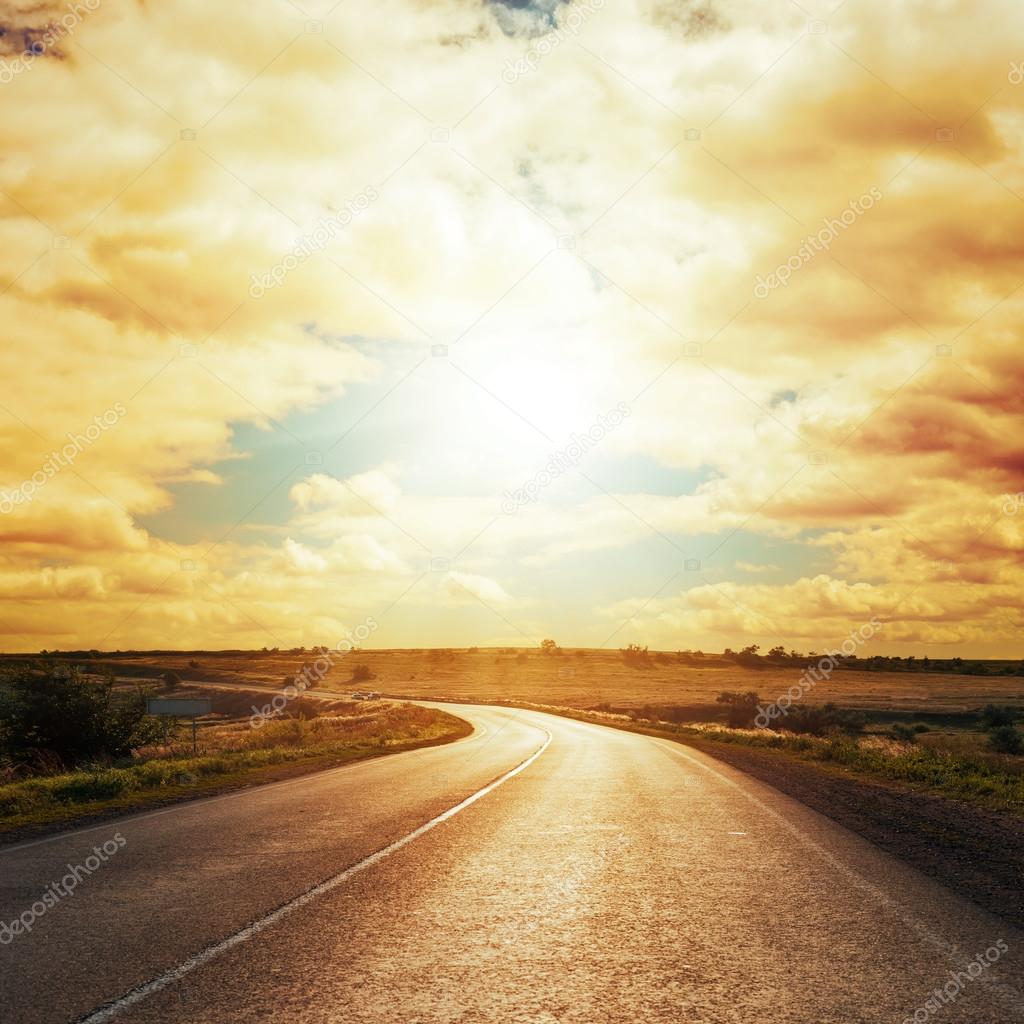 dramatic sunset in clouds over asphalt road