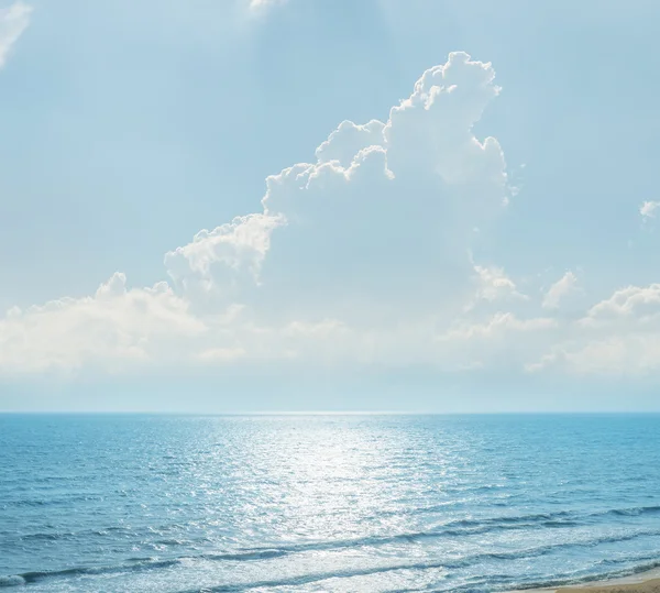 Wolken met zonnestralen over blauwe zee met reflecties — Stockfoto