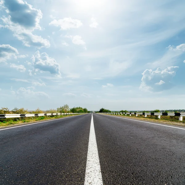 Sun in dramatic sky over asphalt road — Stock Photo, Image